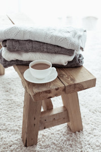 Still life details, stack of winter sweaters on rustic bench on